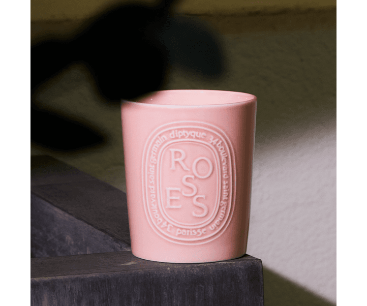 Rose scented candle in a light pink vessel on a ledge